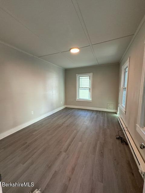 empty room with a baseboard radiator, ornamental molding, and dark hardwood / wood-style floors