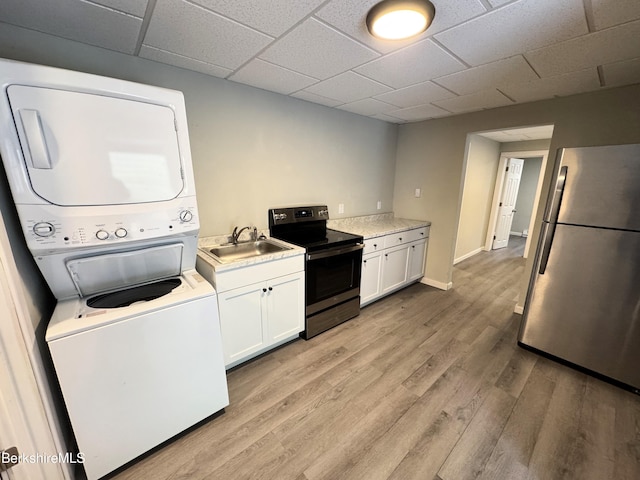 kitchen featuring sink, white cabinets, stacked washer and clothes dryer, light hardwood / wood-style floors, and stainless steel appliances