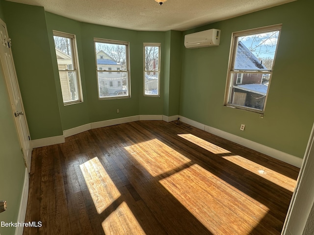 spare room featuring an AC wall unit, dark hardwood / wood-style floors, and a textured ceiling