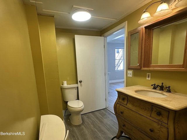 bathroom with wood-type flooring, toilet, and vanity