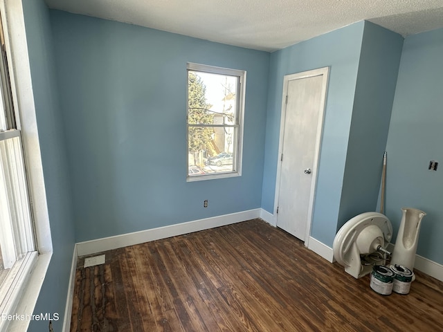 spare room featuring dark wood-type flooring and a textured ceiling