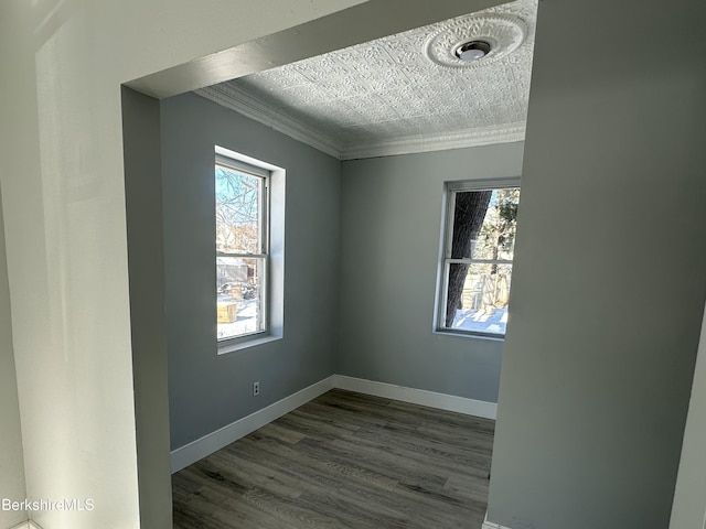 spare room featuring crown molding, wood-type flooring, and a wealth of natural light