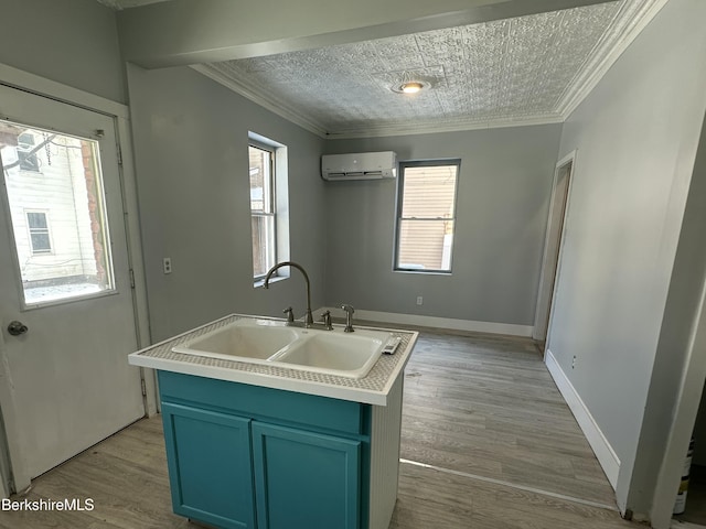 kitchen featuring blue cabinetry, sink, a wall mounted AC, light hardwood / wood-style flooring, and an island with sink