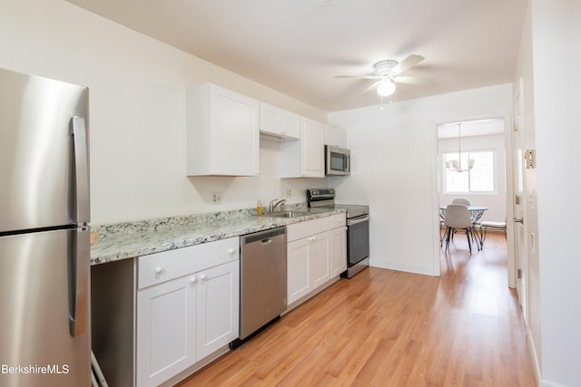 kitchen with appliances with stainless steel finishes, light wood-style floors, white cabinetry, a sink, and ceiling fan