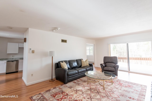 living area with light wood-type flooring, visible vents, baseboards, and baseboard heating