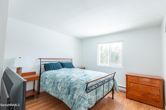 bedroom with a baseboard radiator and wood finished floors