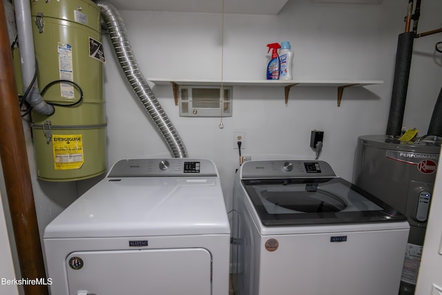 washroom with water heater, laundry area, separate washer and dryer, and visible vents