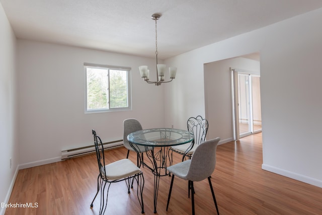 dining room with baseboard heating, an inviting chandelier, wood finished floors, and baseboards