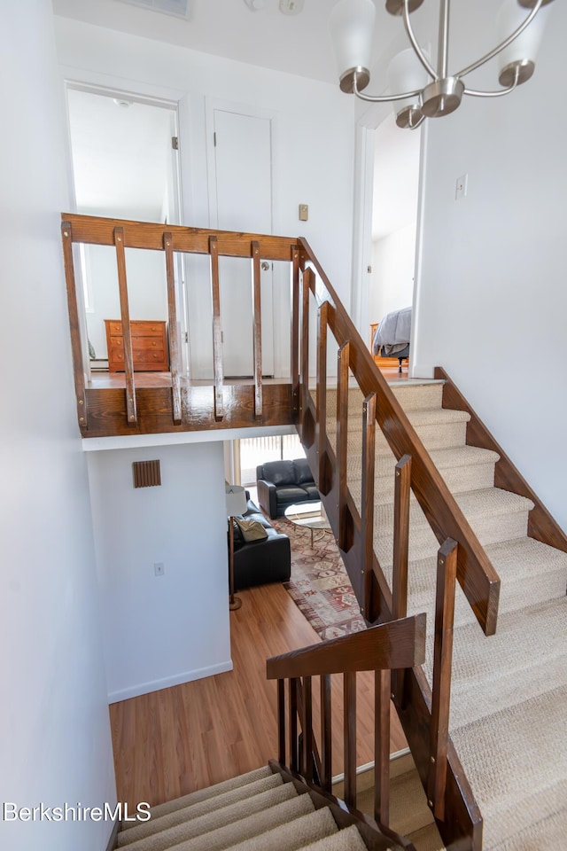 stairway featuring a notable chandelier and wood finished floors