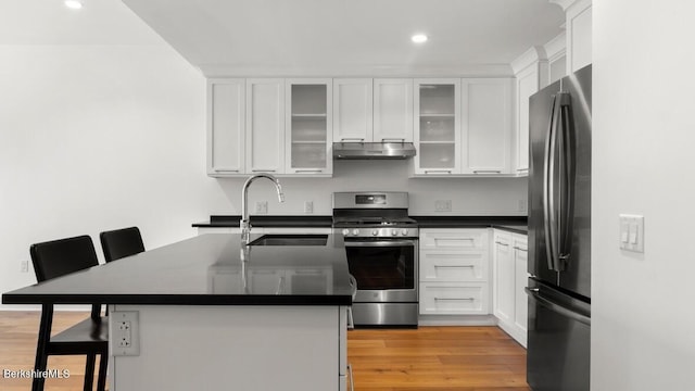 kitchen with white cabinetry, sink, a breakfast bar area, appliances with stainless steel finishes, and light wood-type flooring