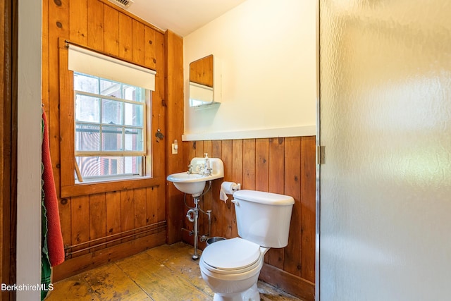 bathroom with wainscoting, toilet, hardwood / wood-style flooring, and wooden walls