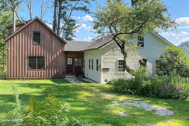 back of house with a lawn, board and batten siding, and a shingled roof