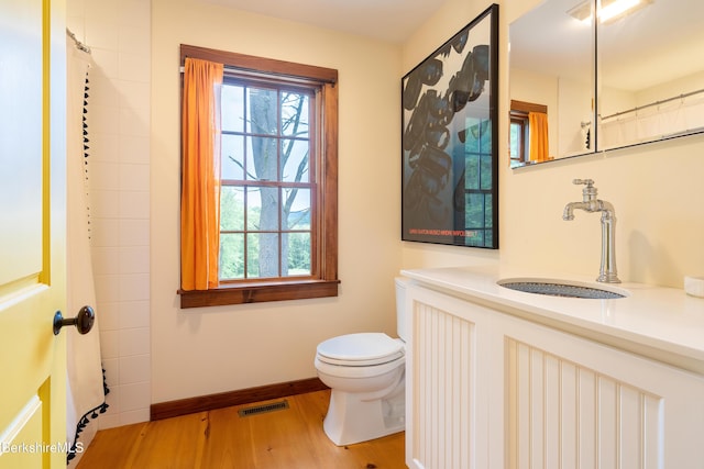 bathroom featuring toilet, visible vents, baseboards, wood finished floors, and vanity