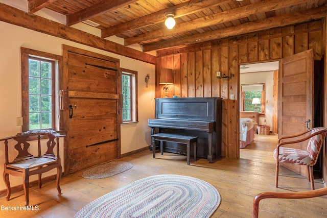 sitting room featuring light wood finished floors, wooden ceiling, and beamed ceiling