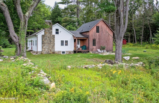 view of front of home with a chimney, a front yard, and a deck