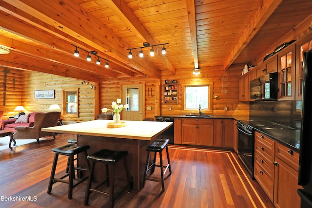 233 Algerie Rd, Becket, MA 01223 - kitchen with black appliances, dark wood-style floors, log walls, a breakfast bar area, and glass insert cabinets