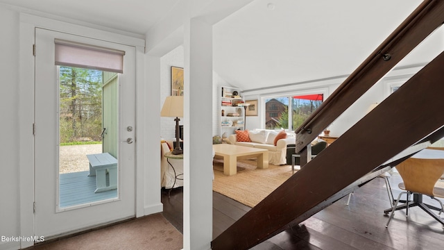 doorway to outside featuring a healthy amount of sunlight, lofted ceiling, and wood finished floors