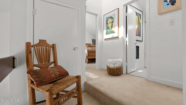 sitting room with baseboards and light carpet