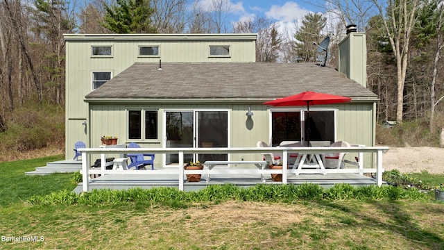 back of house featuring a deck, a chimney, and roof with shingles