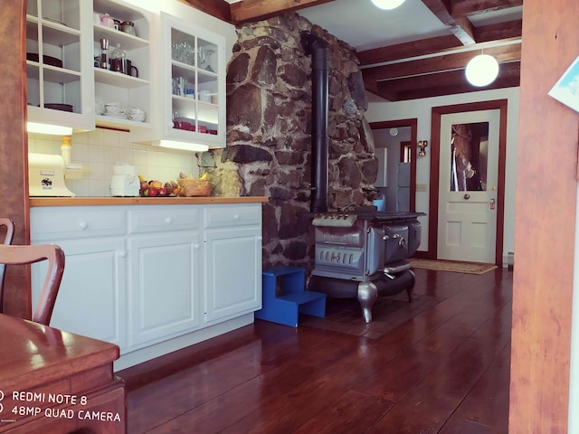 bar with decorative backsplash, white cabinetry, a wood stove, and dark wood-type flooring