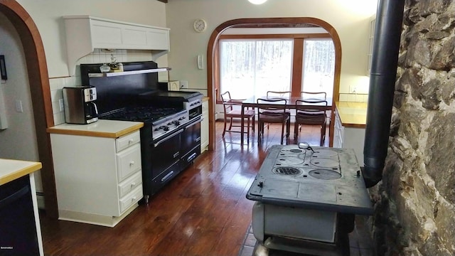 kitchen with backsplash, white cabinetry, high end black range, and dark wood-type flooring