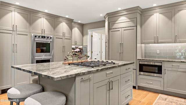 13 Taconic Ave, Lenox, MA 01240 - kitchen with stainless steel appliances, gray cabinets, light wood-style flooring, light stone countertops, and a kitchen breakfast bar