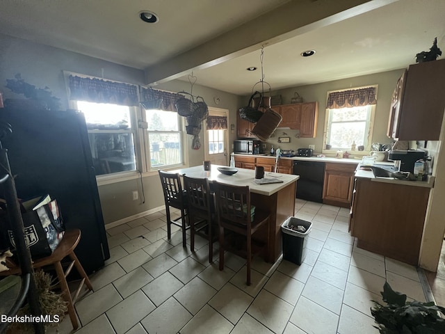 kitchen with a kitchen breakfast bar, black appliances, beam ceiling, decorative light fixtures, and a kitchen island