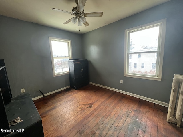 unfurnished bedroom featuring radiator, ceiling fan, and dark wood-type flooring