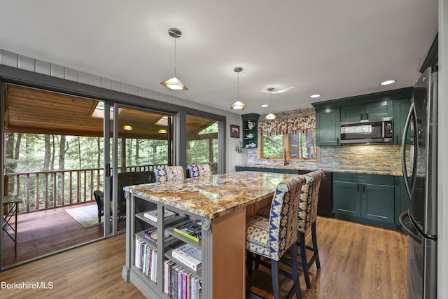 171 Lake Shore Dr, Otis, MA 01253 - kitchen with freestanding refrigerator, stainless steel microwave, green cabinets, backsplash, and light stone countertops
