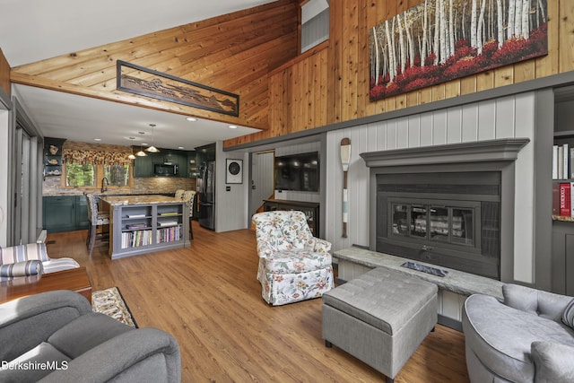 171 Lake Shore Dr, Otis, MA 01253 - living room with a glass covered fireplace, light wood-type flooring, high vaulted ceiling, ceiling fan, and wooden walls