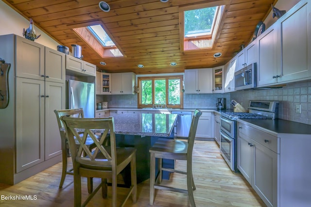 144 Shore Rd, Richmond, MA 01254 - kitchen featuring appliances with stainless steel finishes, a skylight, wood ceiling, a kitchen island, and a kitchen breakfast bar