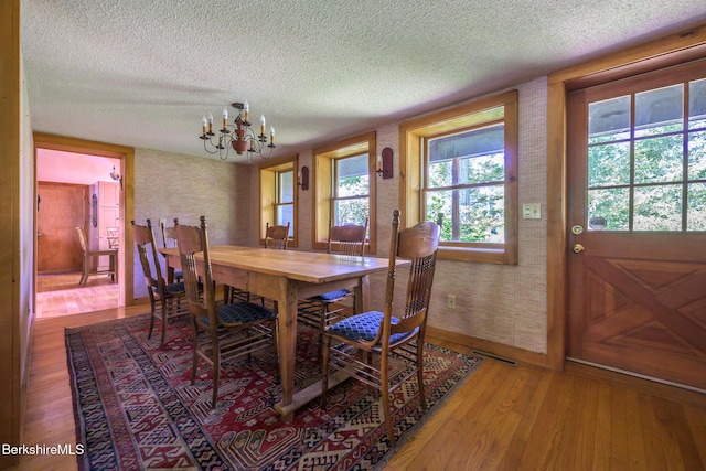 144 Shore Rd, Richmond, MA 01254 - dining space featuring a textured ceiling, a chandelier, wood-type flooring, healthy amount of natural light, and wallpapered walls