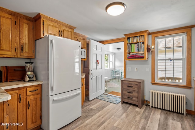 160 Marion Ave, North Adams, MA 01247 - kitchen featuring radiator, freestanding refrigerator, light wood-type flooring, light countertops, and brown cabinets