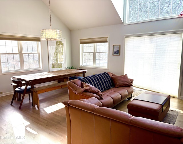 living room featuring high vaulted ceiling, light wood-type flooring, and a wealth of natural light