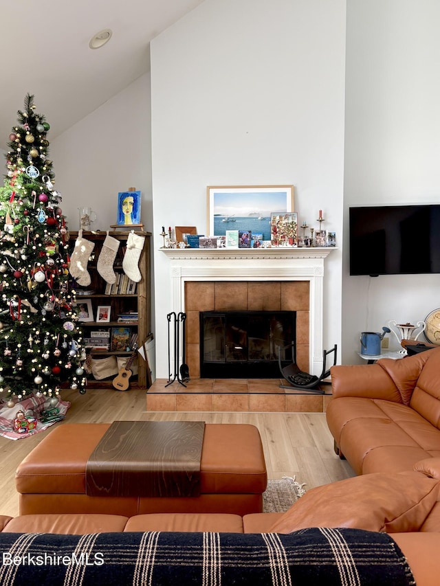 living room with a fireplace, lofted ceiling, and hardwood / wood-style flooring