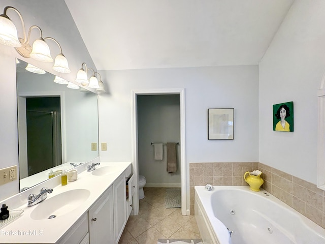 bathroom with tile patterned flooring, a relaxing tiled tub, toilet, and vanity