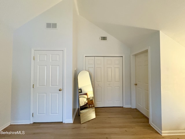 hallway with light hardwood / wood-style floors and lofted ceiling