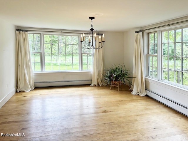unfurnished dining area with a baseboard heating unit, a chandelier, plenty of natural light, and light wood-type flooring
