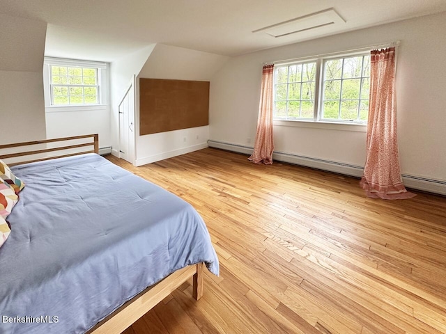 bedroom featuring vaulted ceiling, hardwood / wood-style floors, baseboard heating, and baseboards