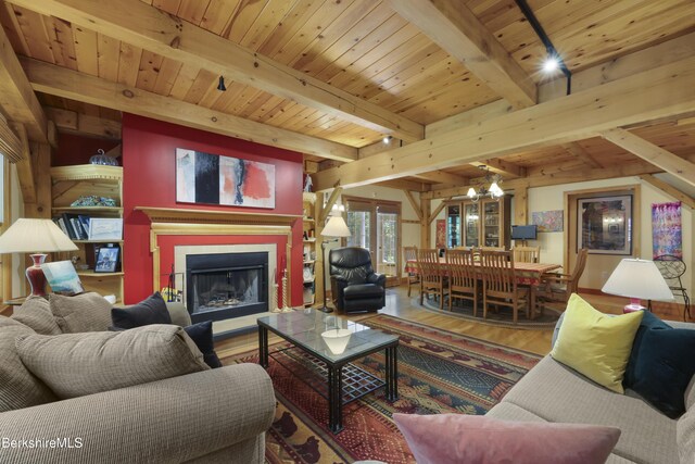 169 Jacobs Hollow Rd, Becket, MA 01223 - living room with wood finished floors, a wooden ceiling with exposed beams, a fireplace with raised hearth, and a chandelier