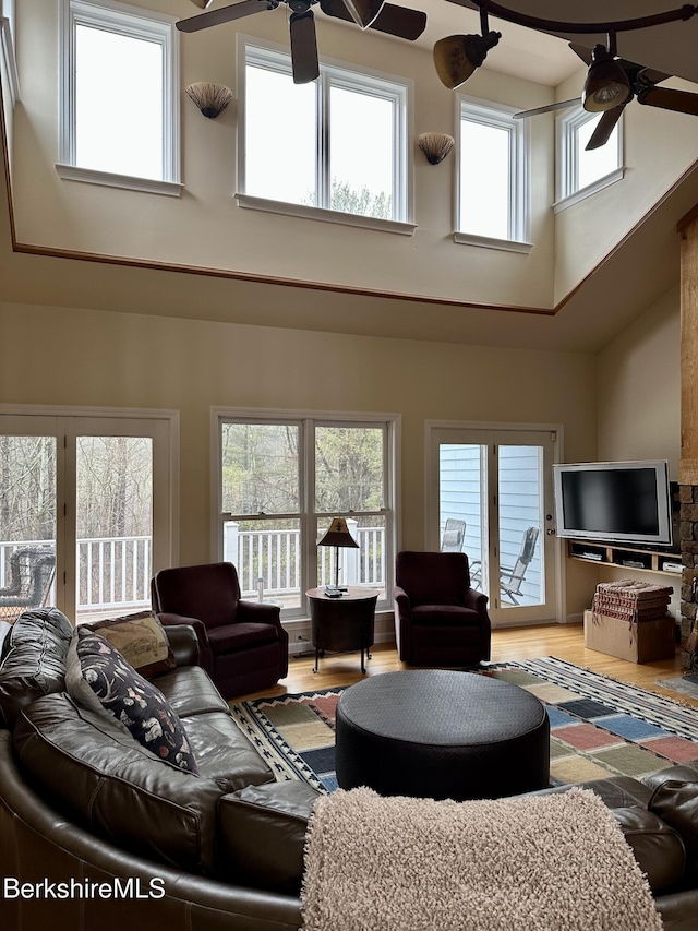 living room featuring wood finished floors, a ceiling fan, and a towering ceiling