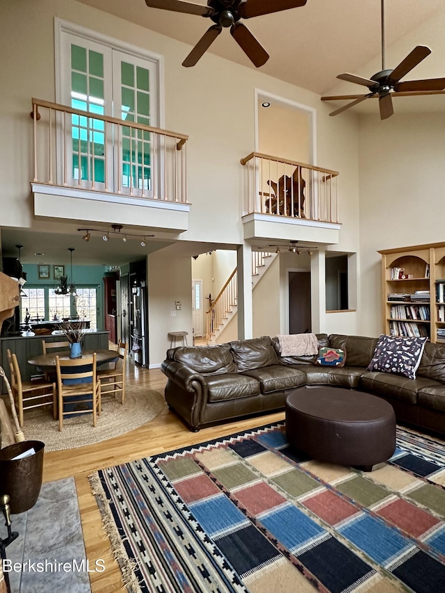 living area featuring a towering ceiling, wood finished floors, and a ceiling fan