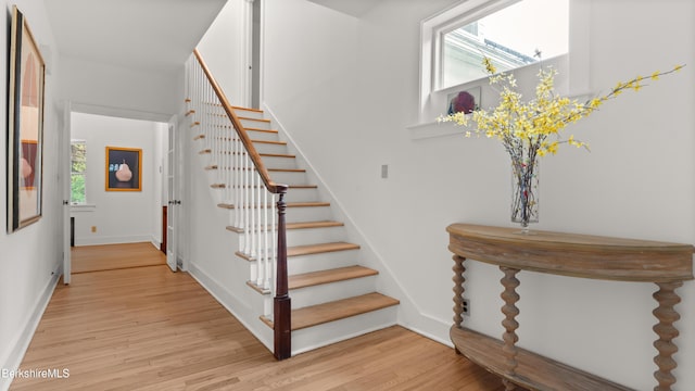 stairway featuring plenty of natural light, wood finished floors, and baseboards