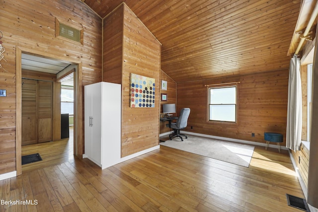 unfurnished office with light wood-type flooring, wood ceiling, wooden walls, and visible vents