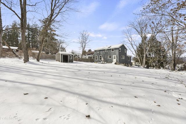 snowy yard with fence and an outdoor structure