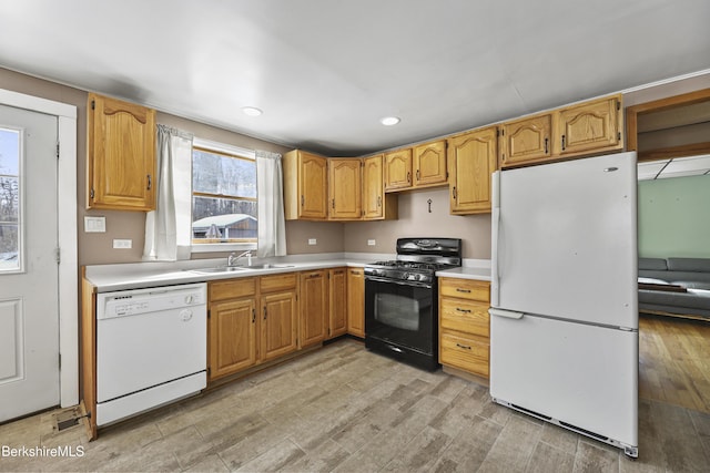 kitchen featuring white appliances, light countertops, light wood-type flooring, a sink, and recessed lighting