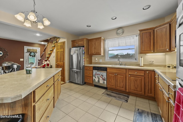 kitchen featuring appliances with stainless steel finishes, sink, a notable chandelier, a kitchen island, and hanging light fixtures