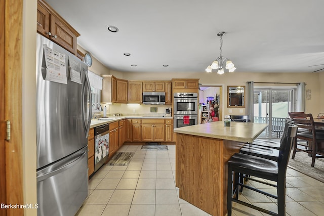 kitchen featuring an inviting chandelier, light tile patterned floors, decorative light fixtures, a kitchen island, and stainless steel appliances