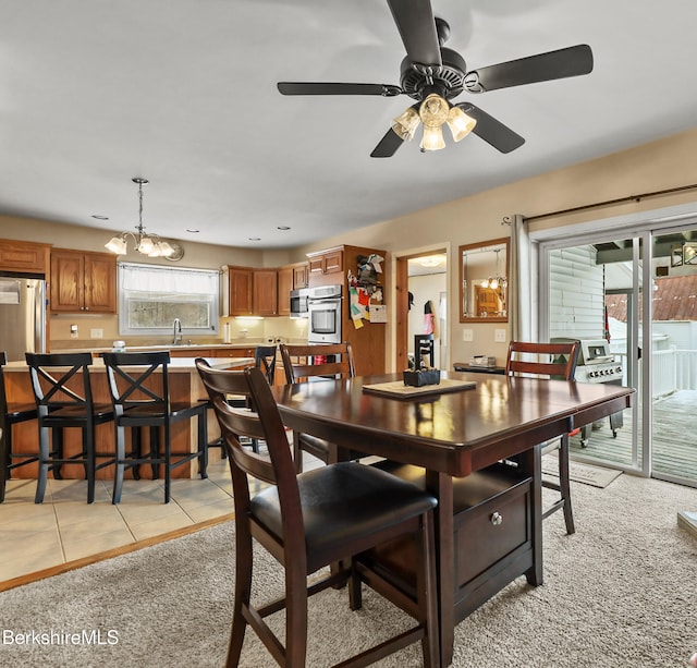 carpeted dining area with sink and ceiling fan with notable chandelier