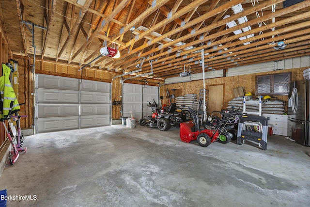 garage featuring stainless steel refrigerator and a garage door opener